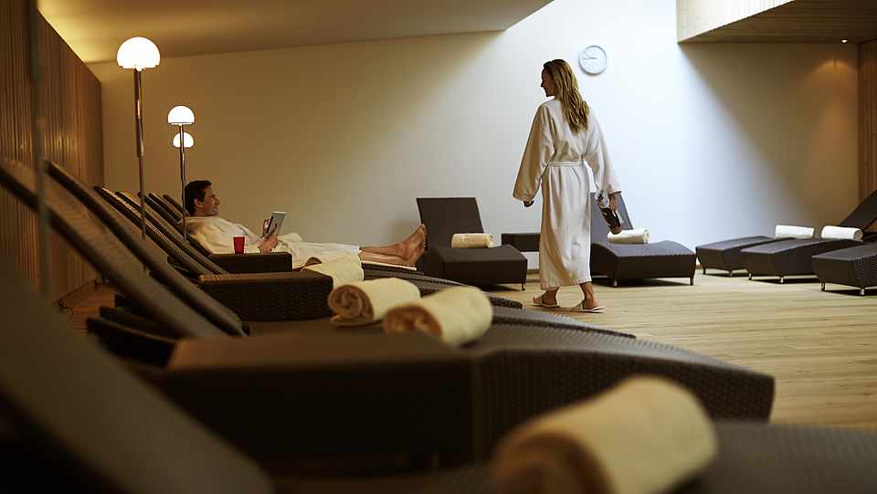 Eine Frau geht zu einer Liege und im Hintergrund liegt ein Mann auf einer Liege