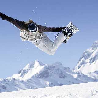 Snowboarder springt mit seinem Board in den Bergen in die Luft