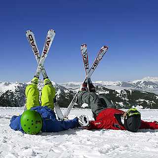 Zwei Menschen liegen im Schnee und strecken ihre Skier in die Luft