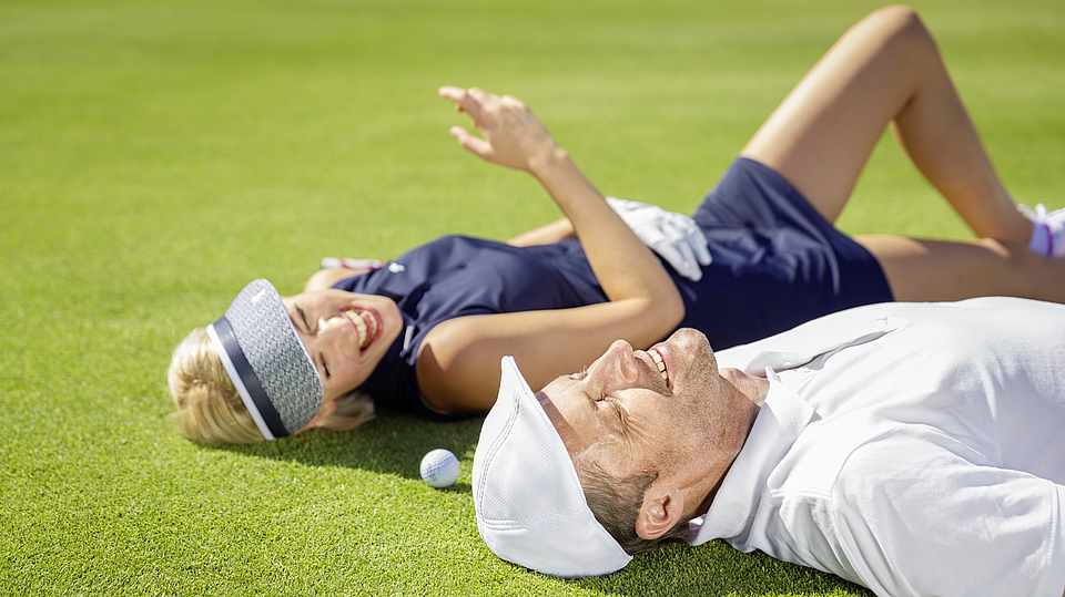 Paar liegt auf dem Green beim Golf spielen