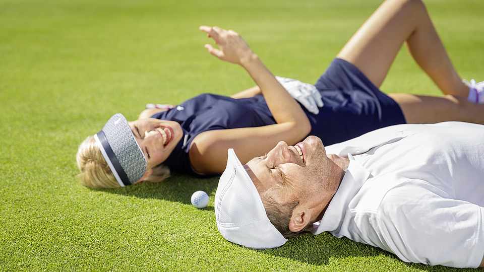 Paar liegt auf dem Green beim Golf spielen