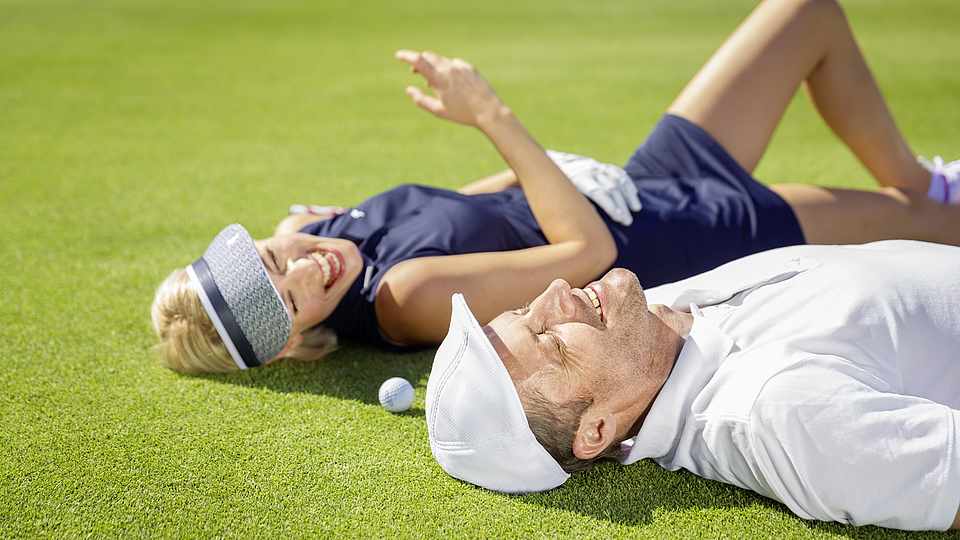 Paar liegt auf dem Green beim Golf spielen