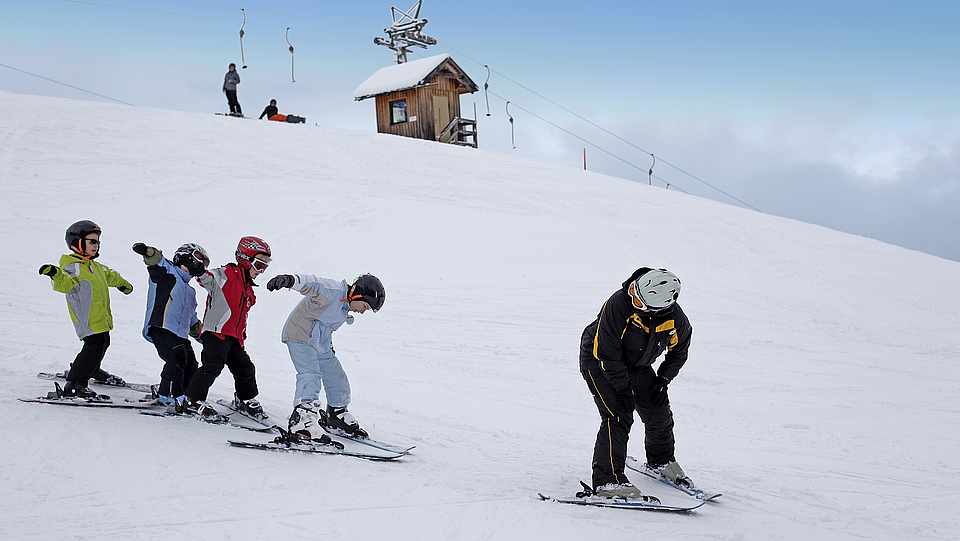 Vier Kinder und ein Trainer die aktiv im Winter Ski fahren 