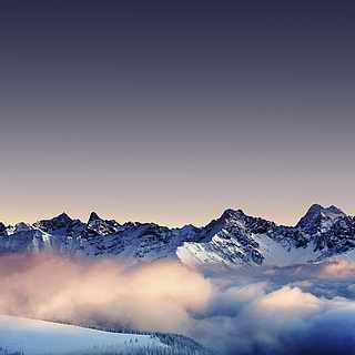 Hohe verschneite Berge, die im Nebel liegen