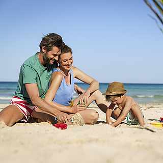 Eltern spielen mit ihrem Kind am Strand
