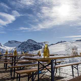 Bänke und Tische stehen draußen vor den Bergen